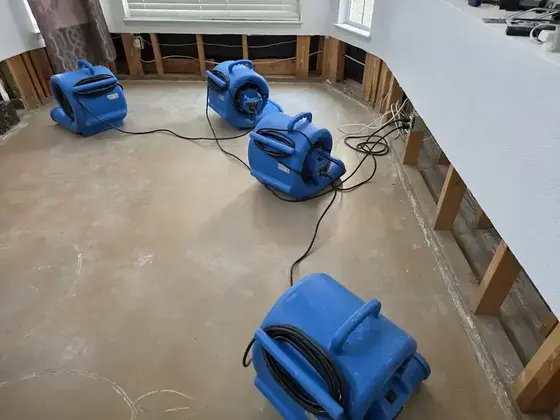 Air movers drying a bare slab in Carrollton after the wet flooring came out
