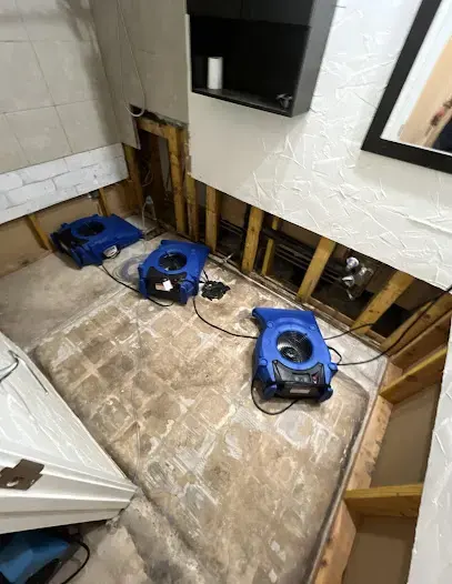 Flood cut drywall and air movers drying a bathroom wall cavity in Carrollton
