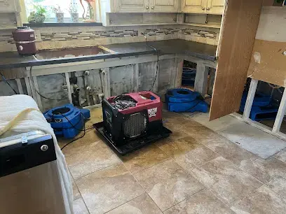Kitchen toe-kicks removed with a dehumidifier drying after a supply line leak