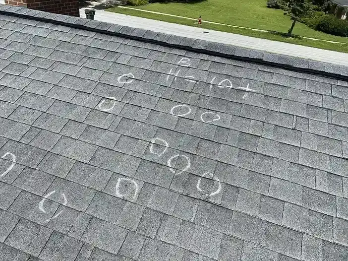 Hail strikes circled in chalk on asphalt shingles after a DFW storm